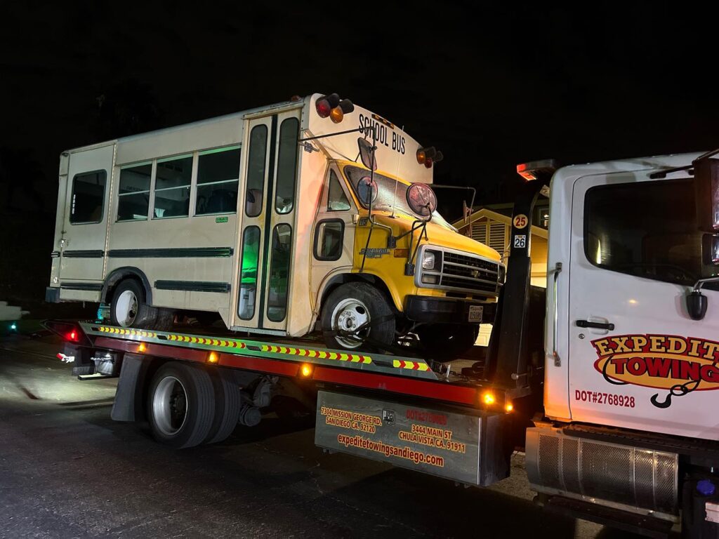 School bus towing service with a flatbed tow truck in San Diego, CA.